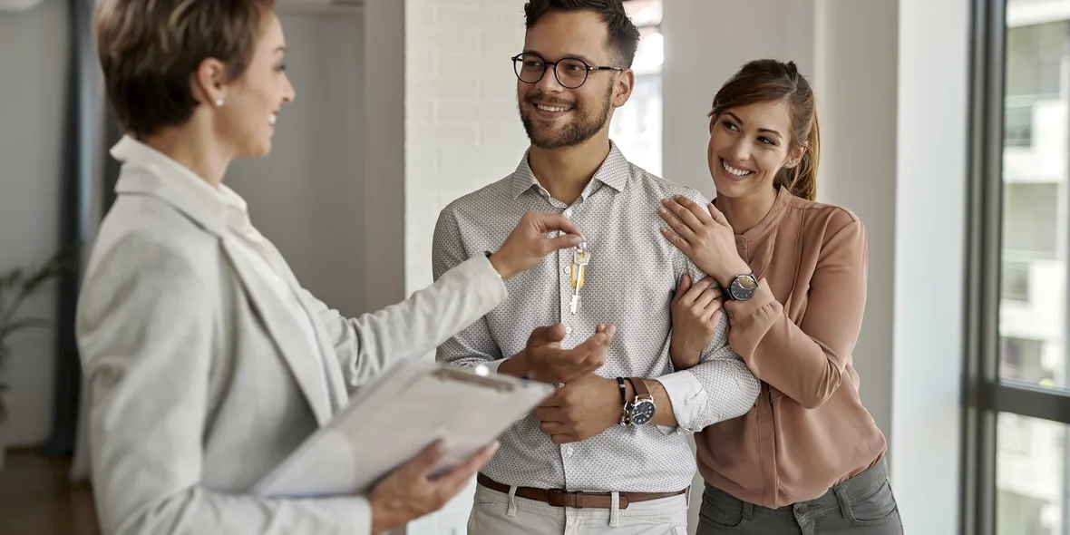 A happy couple buys a new house and gets the keys from a real estate agent