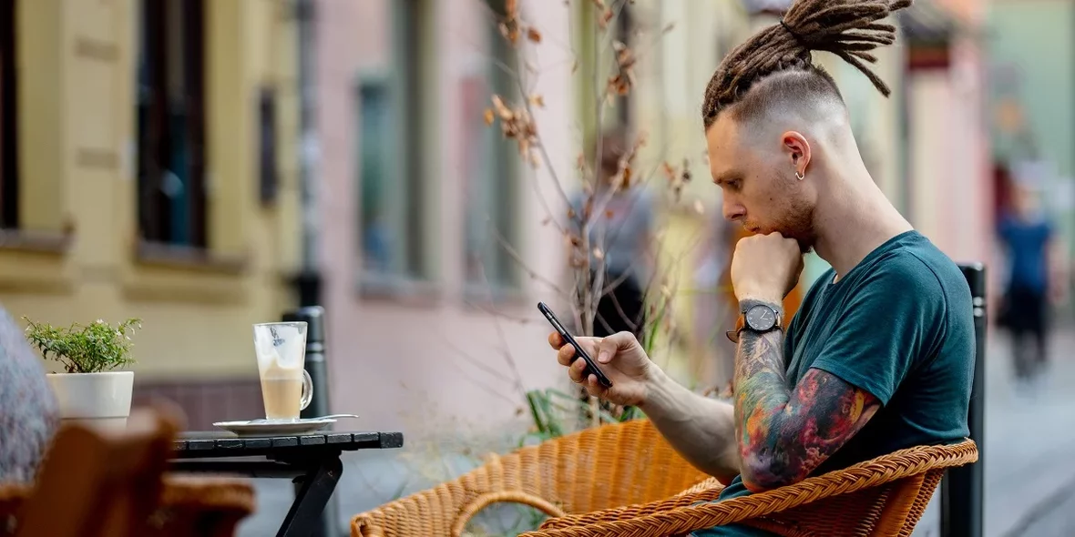 Цифровой кочевник сидит в телефоне в кафе