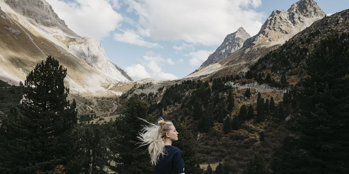 Switzerland, Graubünden, Albula Pass, young woman standing in a mountainous landscape
