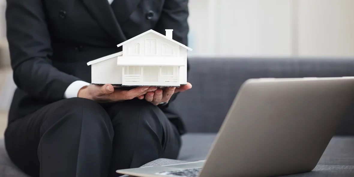 Ein Immobilienmakler mit einem kleinen Modell eines Hauses in der Hand
