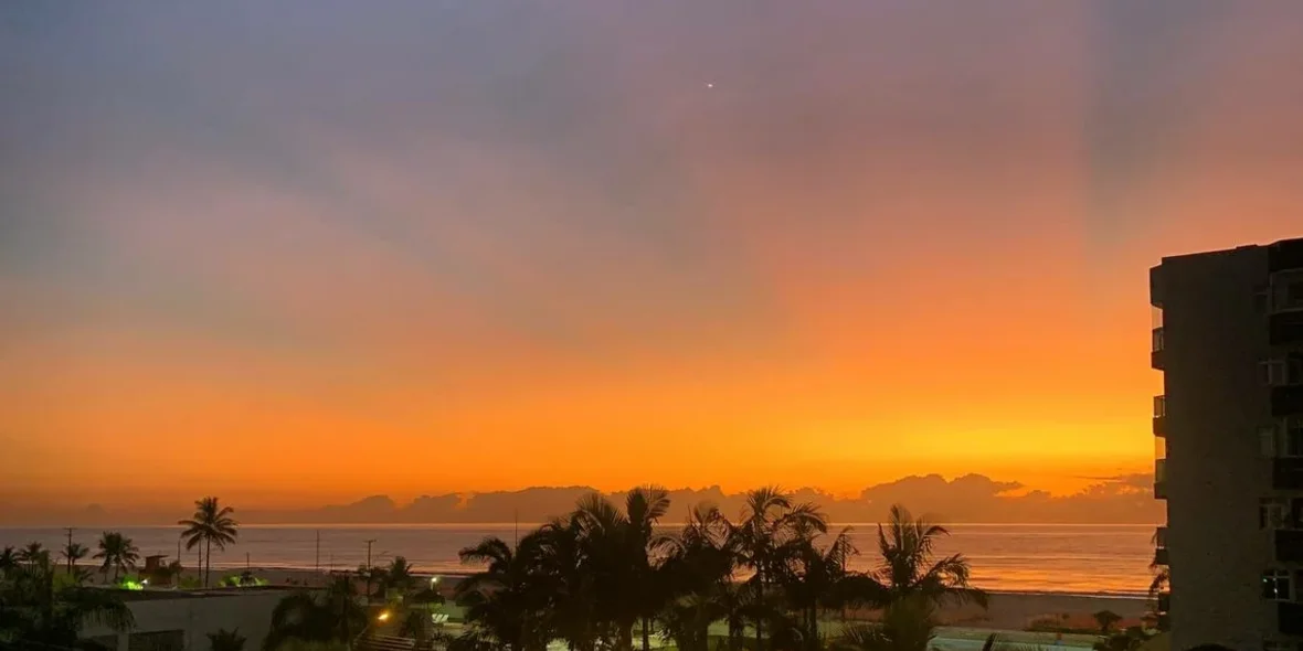 Вид из окна на закат и пальмы в Бразилии
