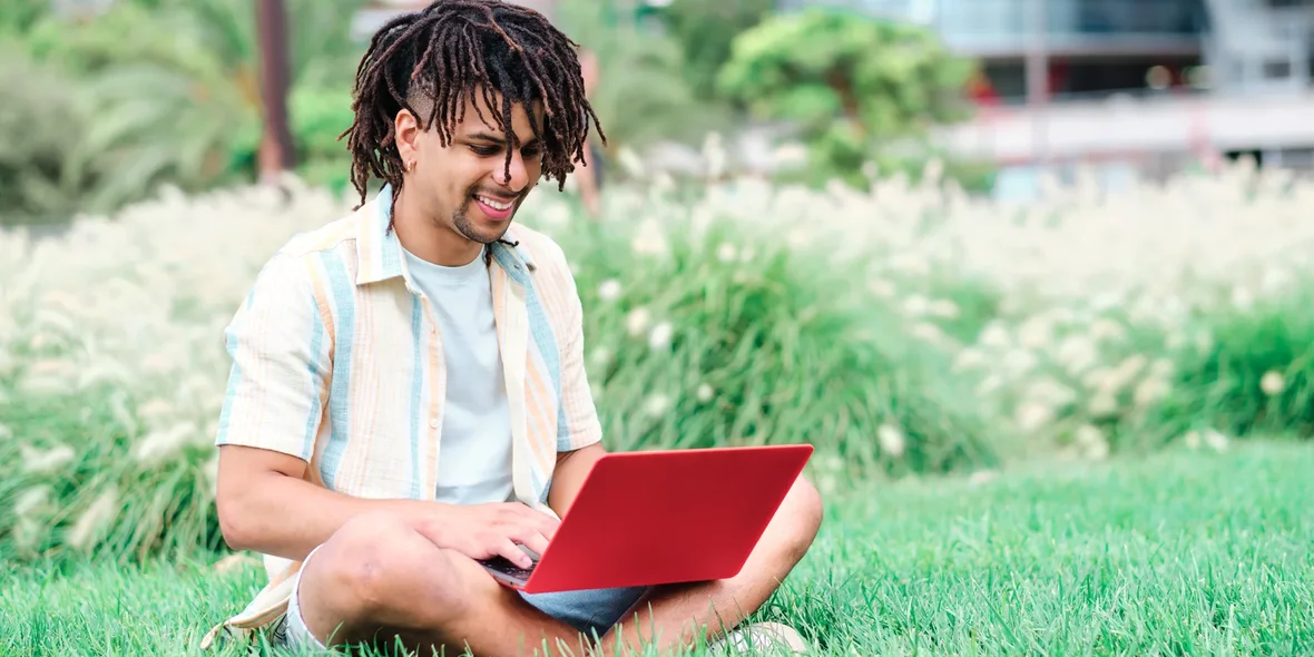 Hispanic man sits at his laptop and smiles. 