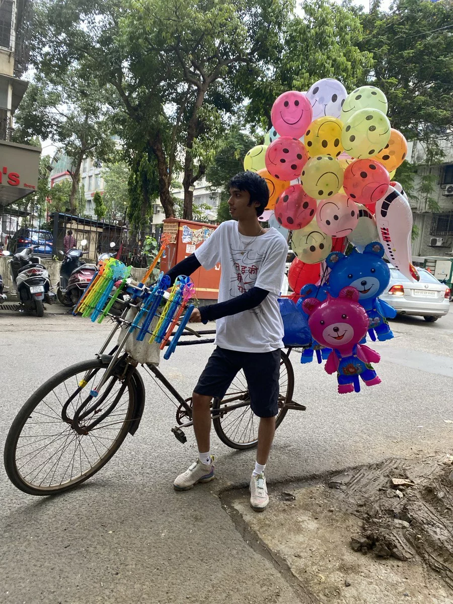 A resident of India stands by a bicycle decorated with colorful balloons