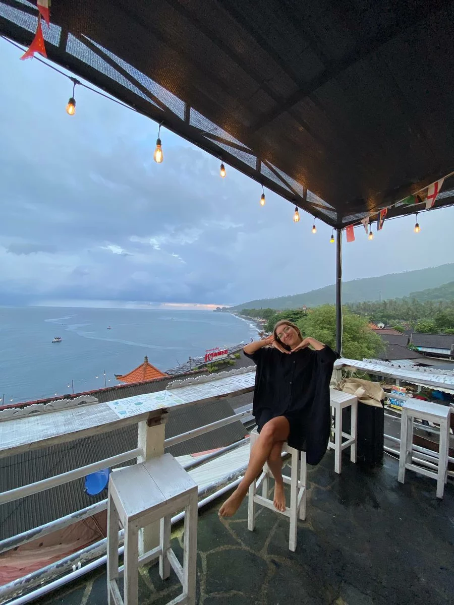 a picture of a girl on a terrace overlooking the ocean.