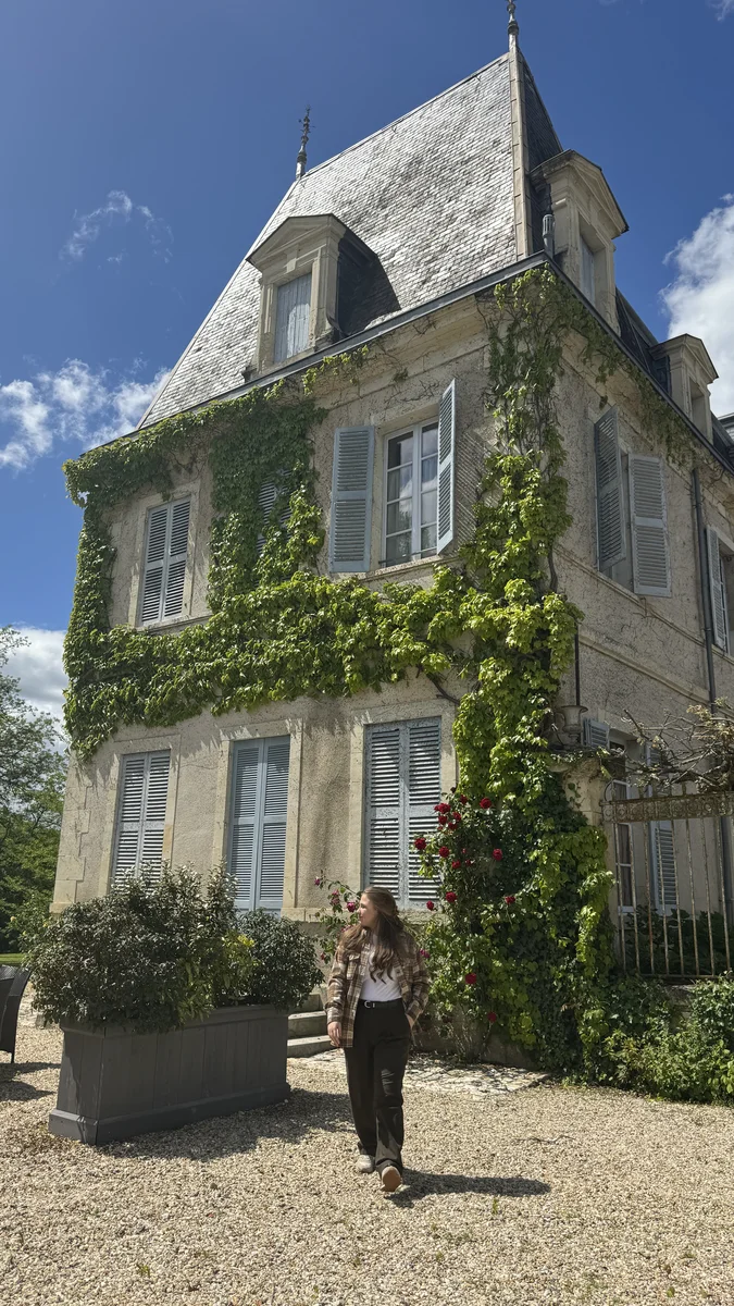 A girl in front of a house covered with greenery