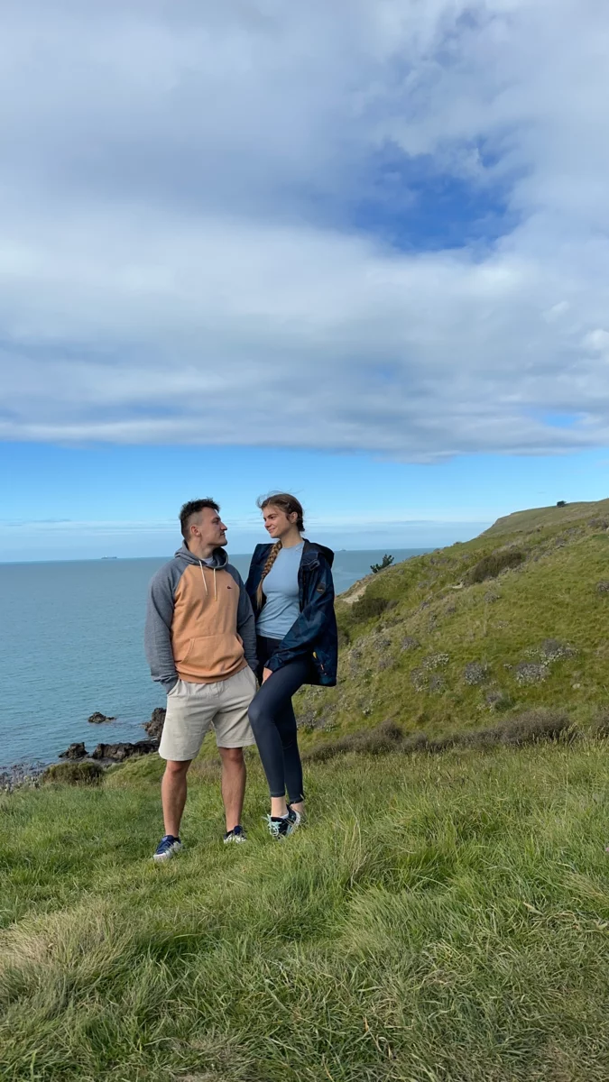A couple in New Zealand, with the ocean in the background