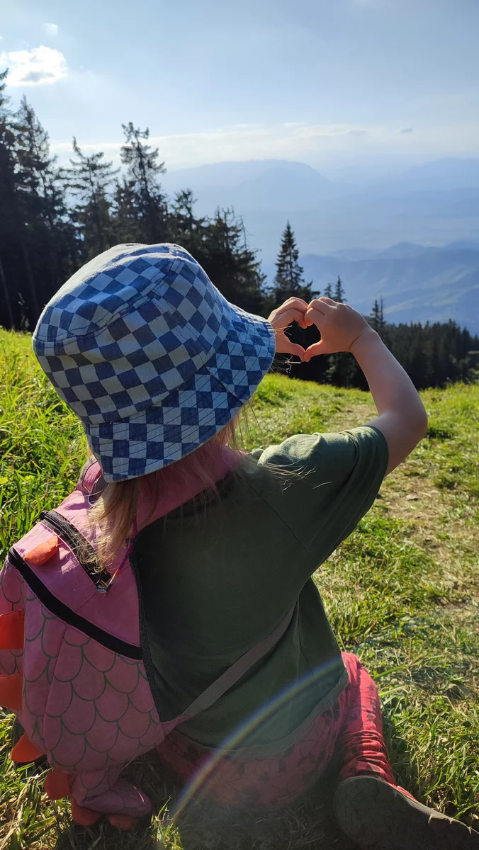 The child makes a heart with his hand