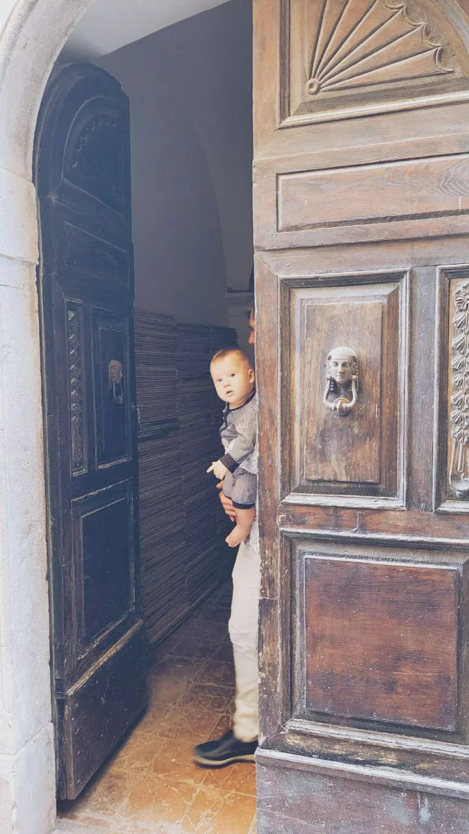 A child peeks out from behind the door
