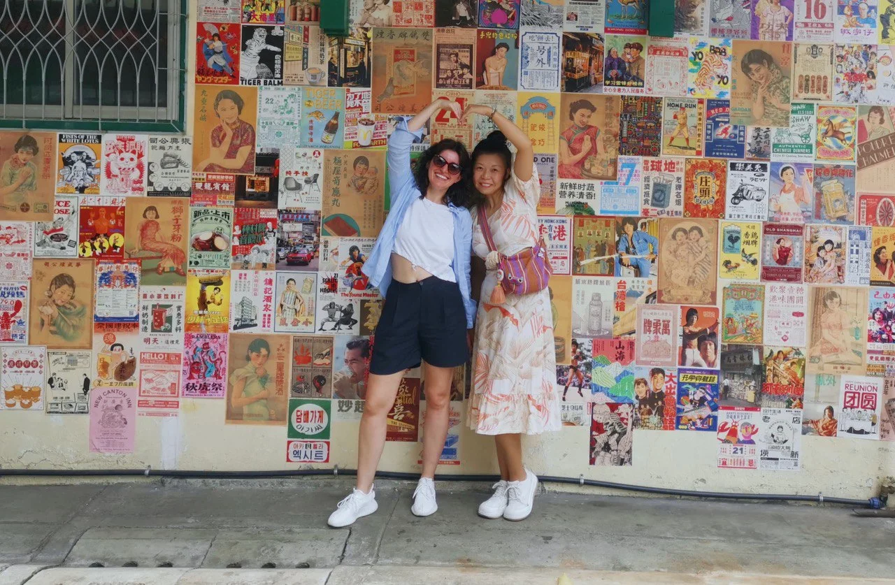 two women standing against the wall and smiling